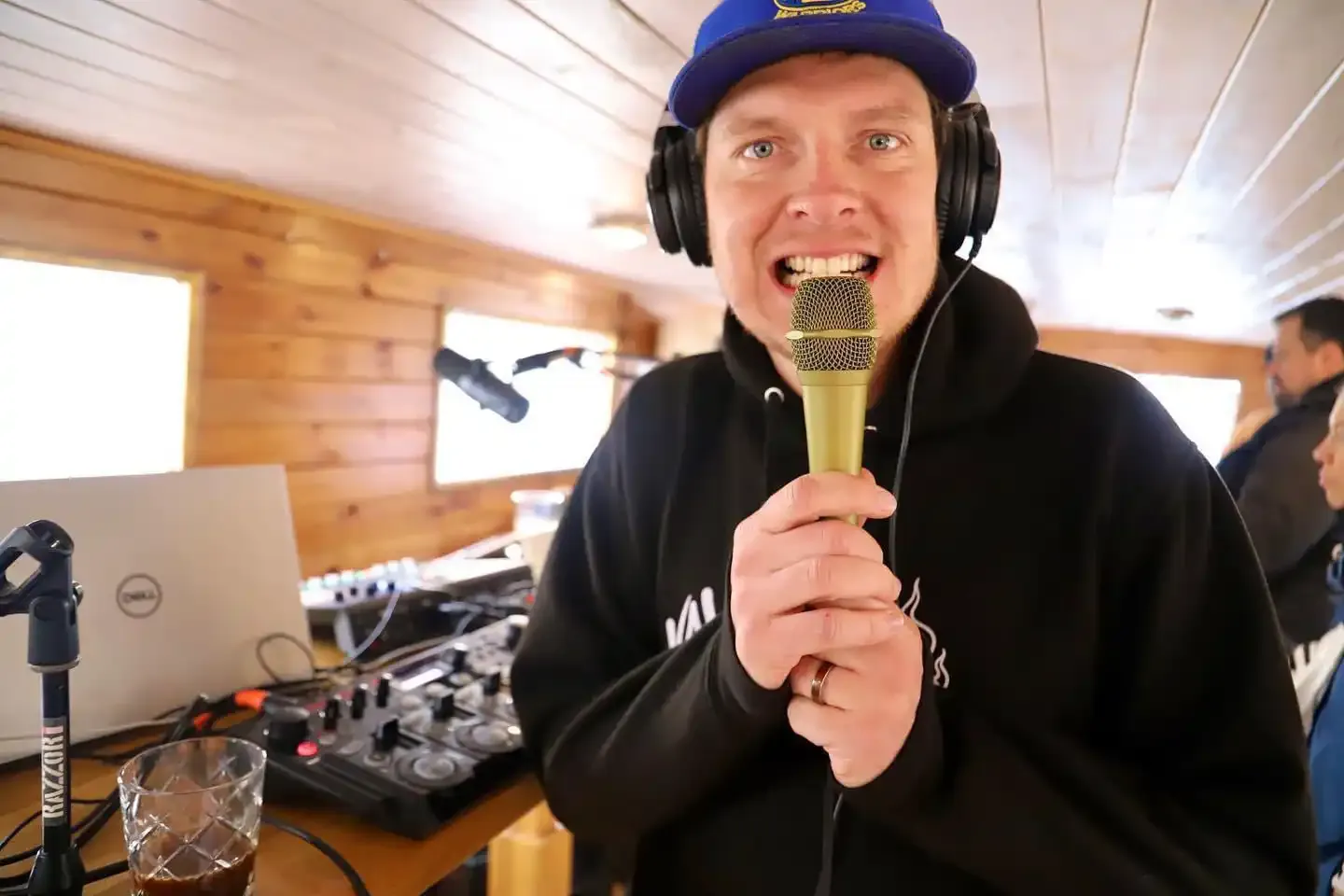 DJ with headphones singing into a microphone at the mixing desk on board