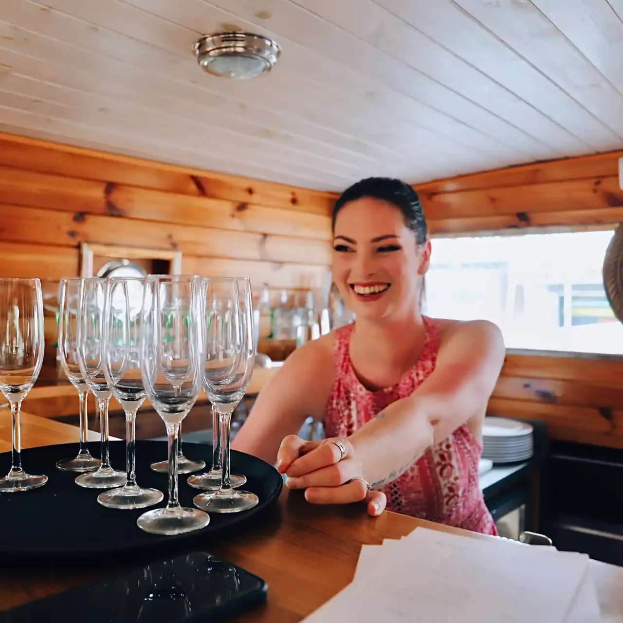 Žena u baru s podnosem plným sklenek na sekt