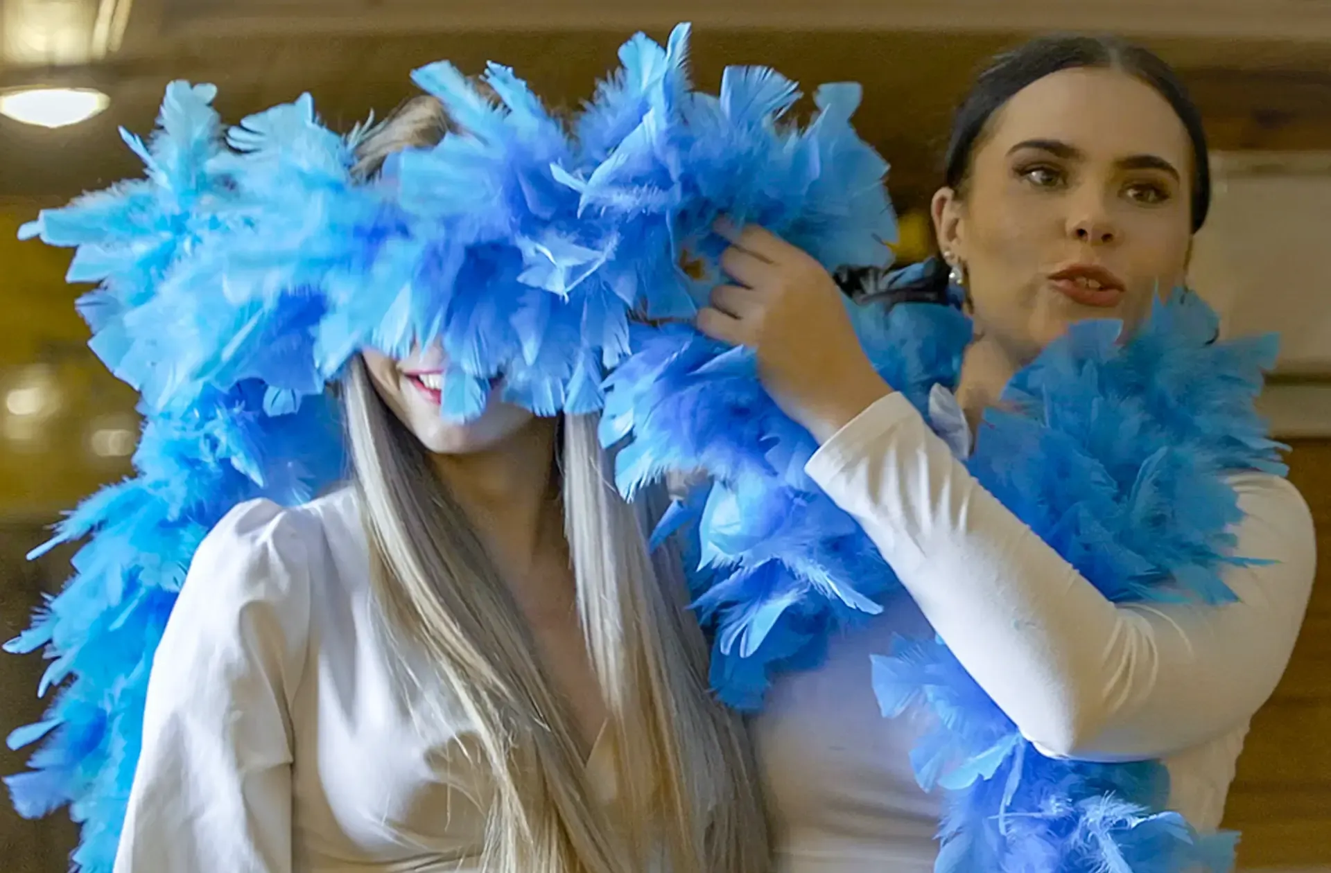 Two women playing with blue feather boas