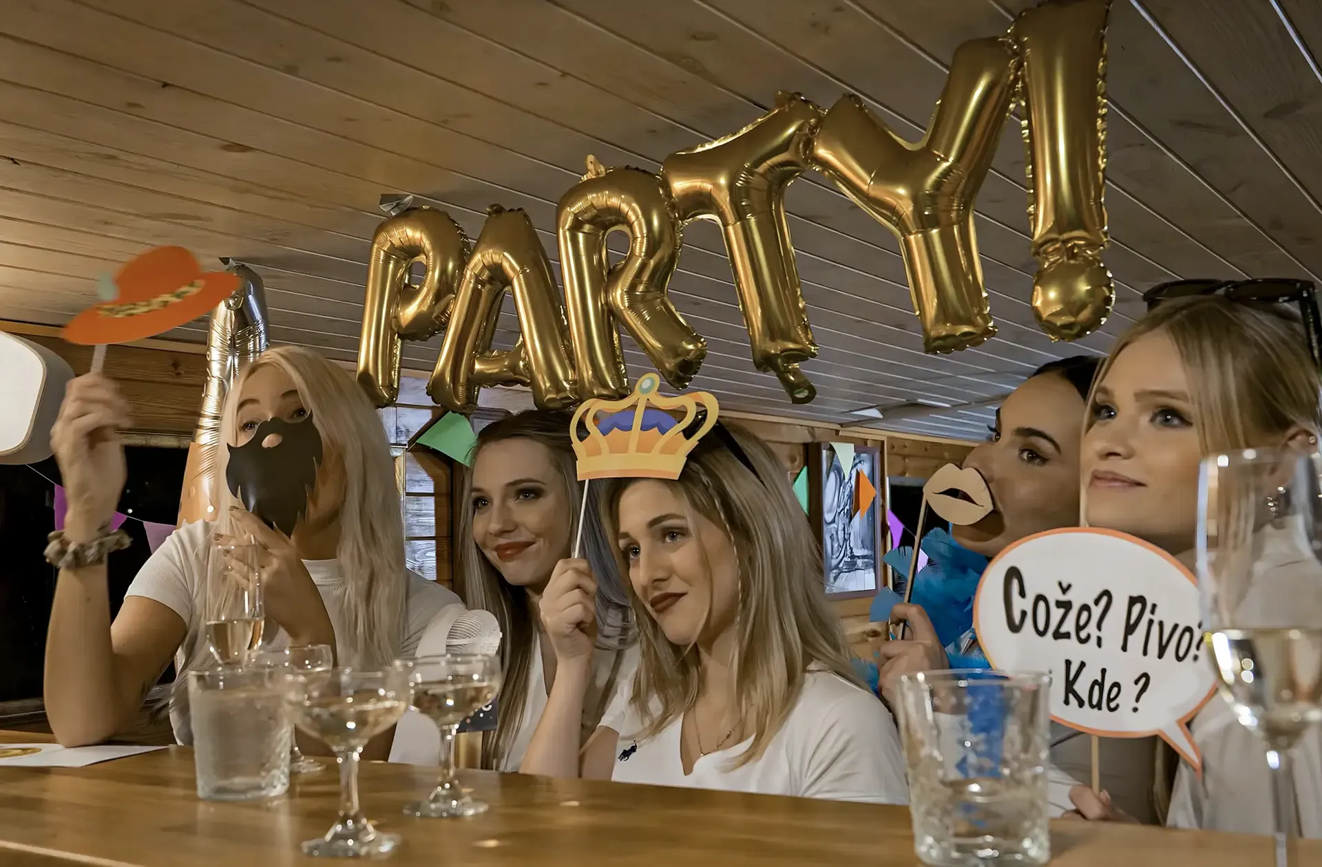 Friends at the bar with photo props and gold PARTY balloons