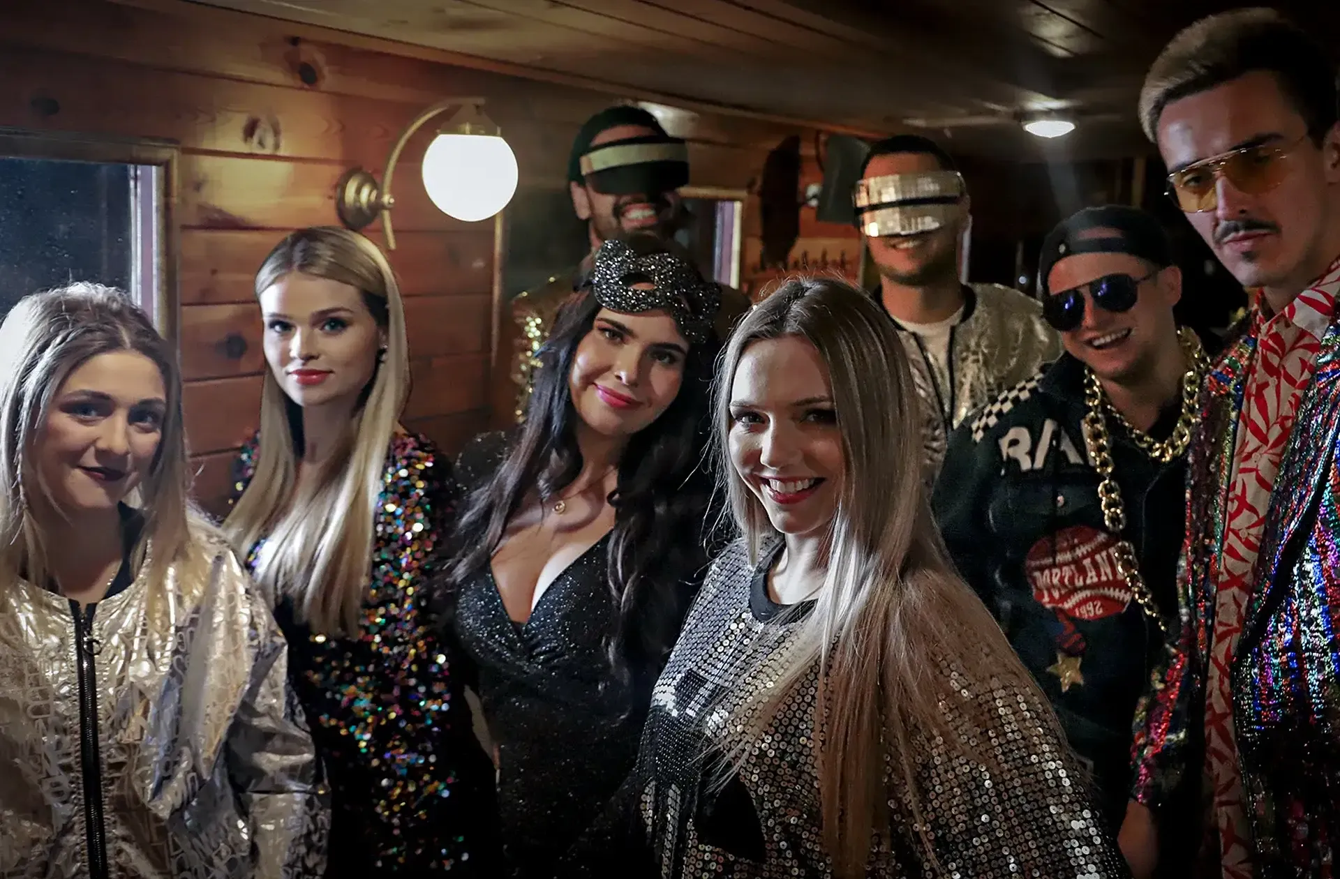 A group of friends in glittery outfits posing in the wood-panelled cabin